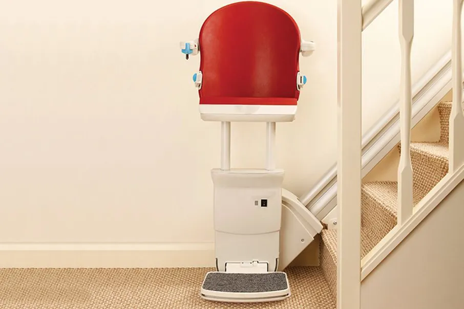 Freedom Stairlifts Straight Stairlift with a perched seat in red upholstery parked at the foot of the stairs