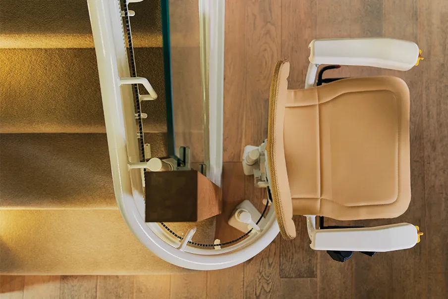 Looking from above at a Freedom Stairlifts Curved Stairlift 1 in natural stone coloured upholstery showing how the stairlift track wraps 180 degrees at the foot of the stairs