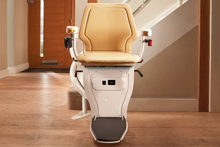 Freedom Stairlifts Curved Stairlift 1 in natural stone coloured upholstery parked at the foot of the stairs witha 180 degree parking bend