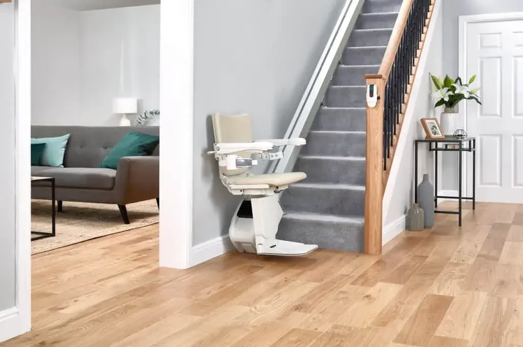 Freedom Stairlifts Straight Stairlift 2 with natural colour upholstery open at the foot of the stairs with the stairlift remote control fixed to the newel post